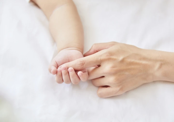 赤ちゃんが母親の人差し指を握っている様子