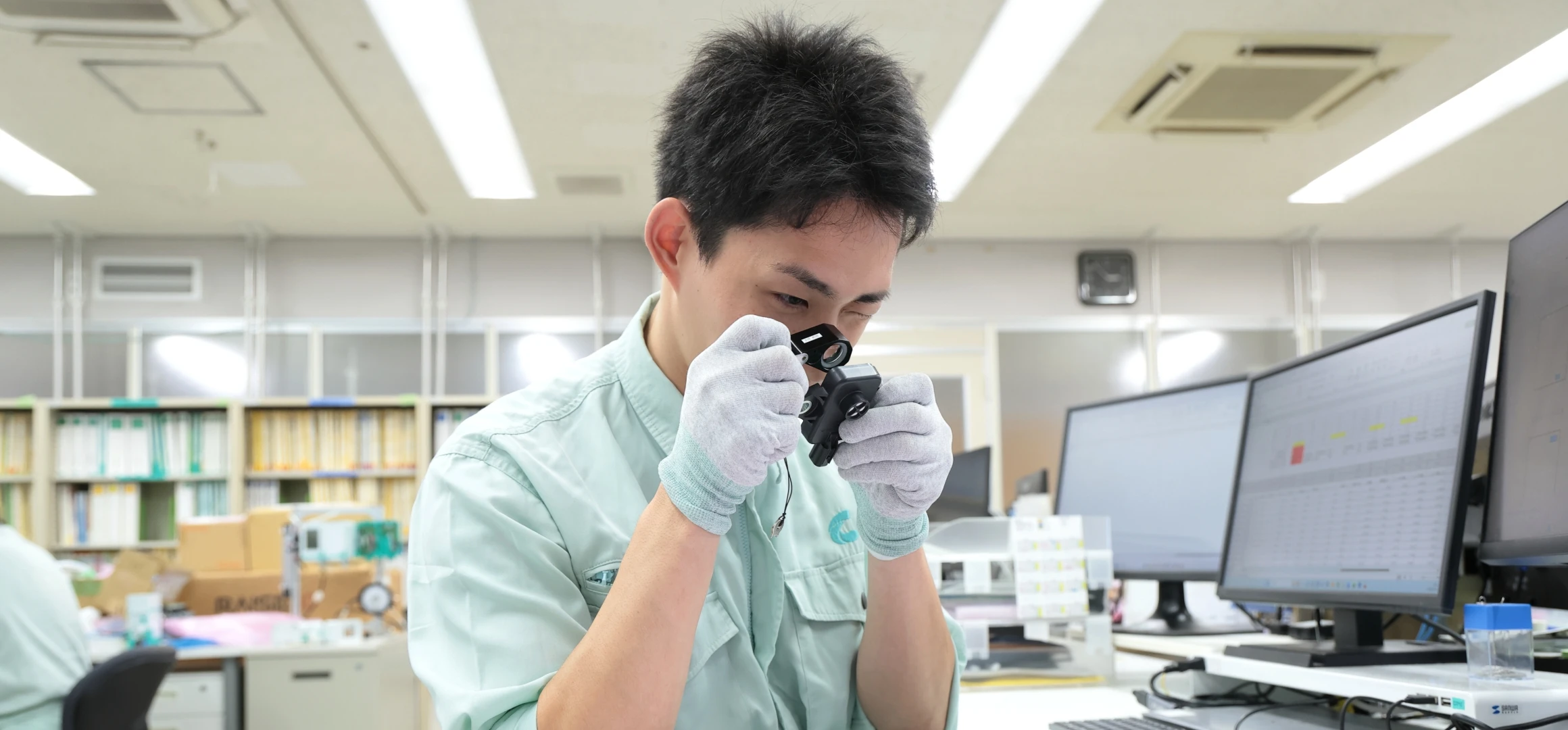 男性社員がルーペで製品を検査している様子