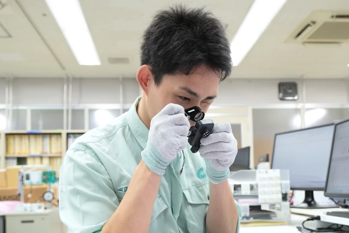 男性社員がルーペで製品を検査している様子