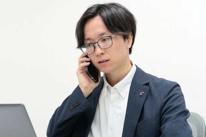 スーツ姿の男性社員が電話で対応している様子