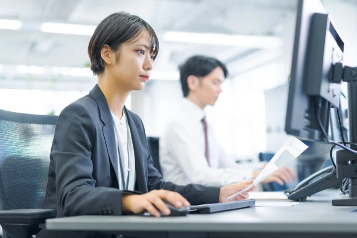 スーツ姿の女性社員が集中して業務に取り組んでいる様子