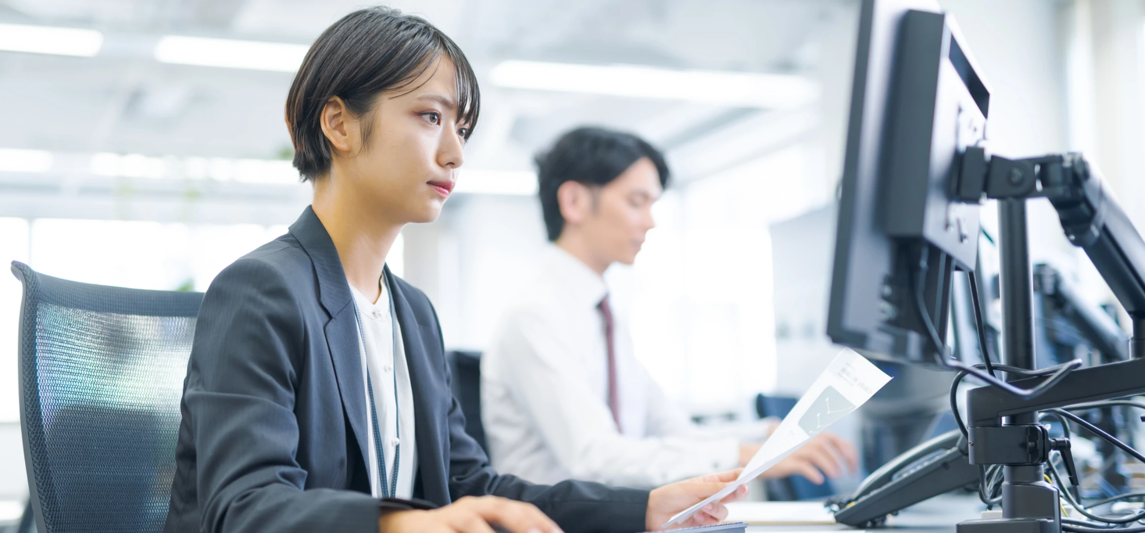 スーツ姿の女性社員が集中して業務に取り組んでいる様子