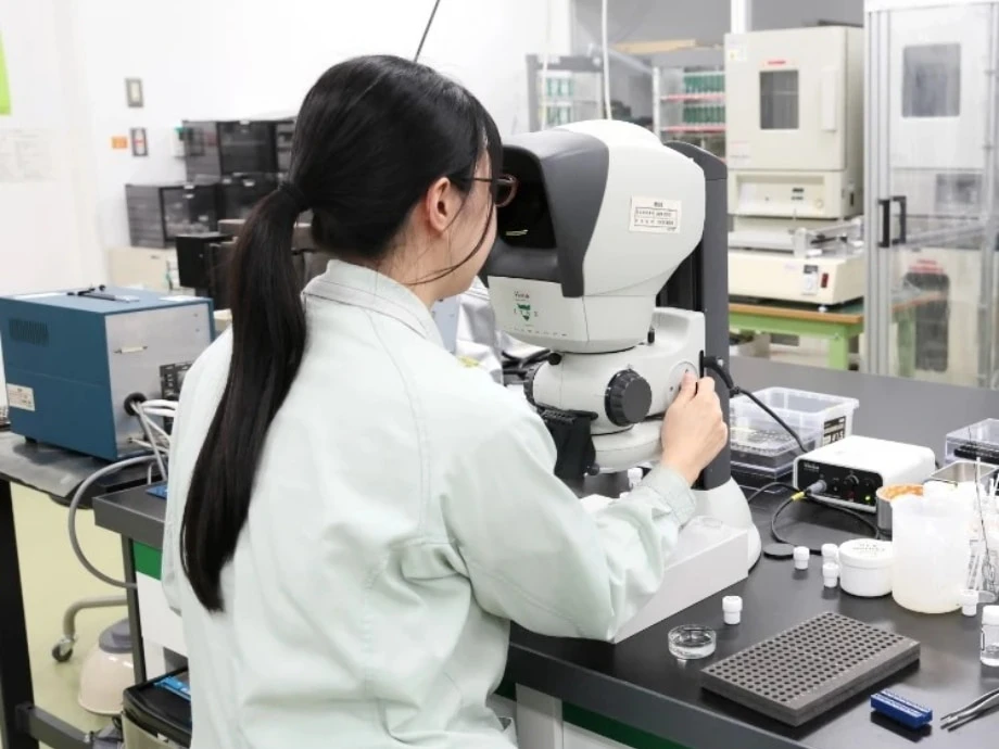 女性社員が顕微鏡を使って作業している様子