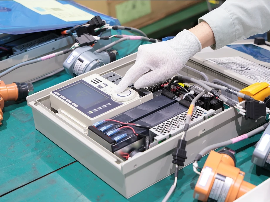 白い手袋を着用した社員が電子部品を修理している様子