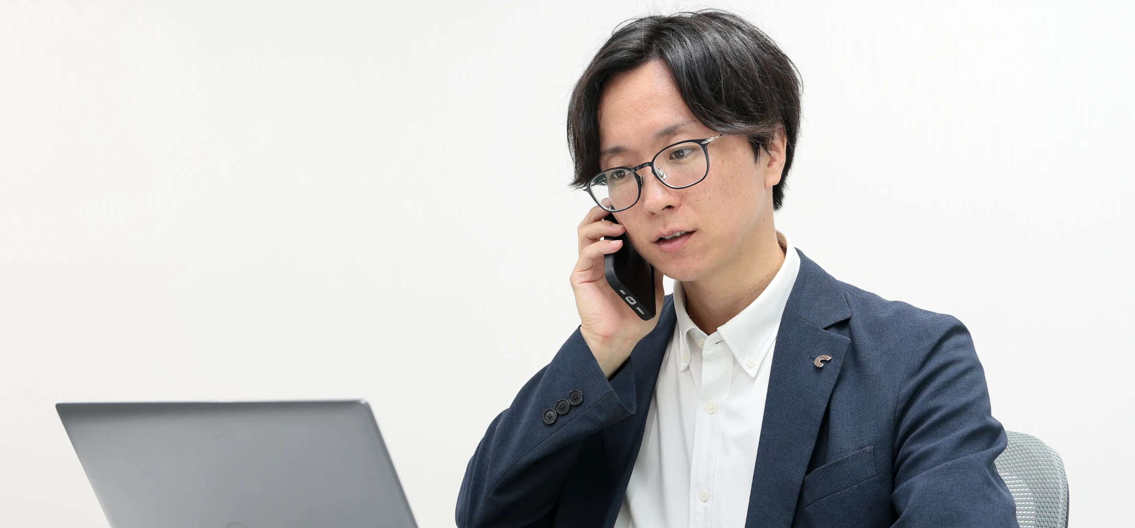 スーツ姿の男性社員が電話で対応している様子