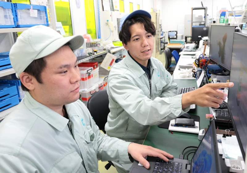 男性社員2名が協力してパソコンで作業している様子