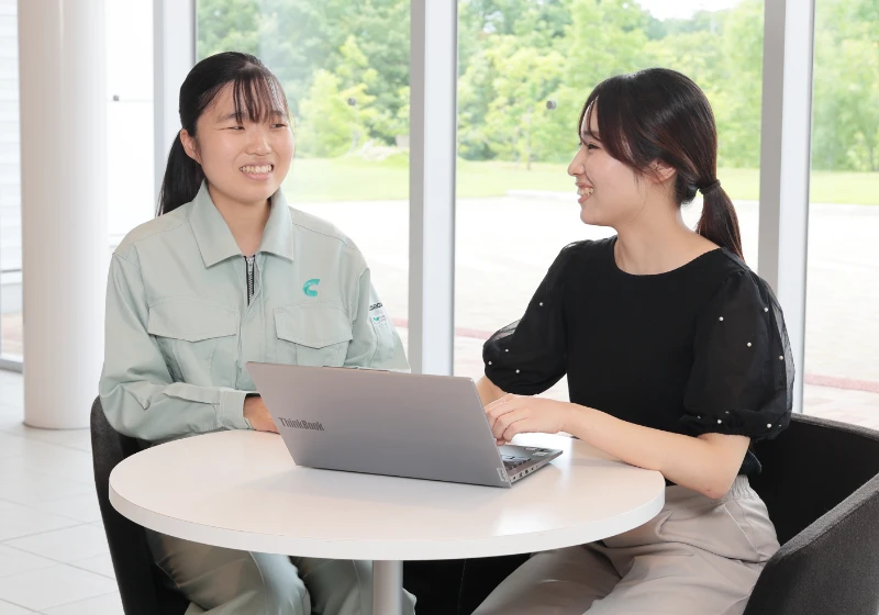 女性社員2名がパソコンのそばで会話している様子