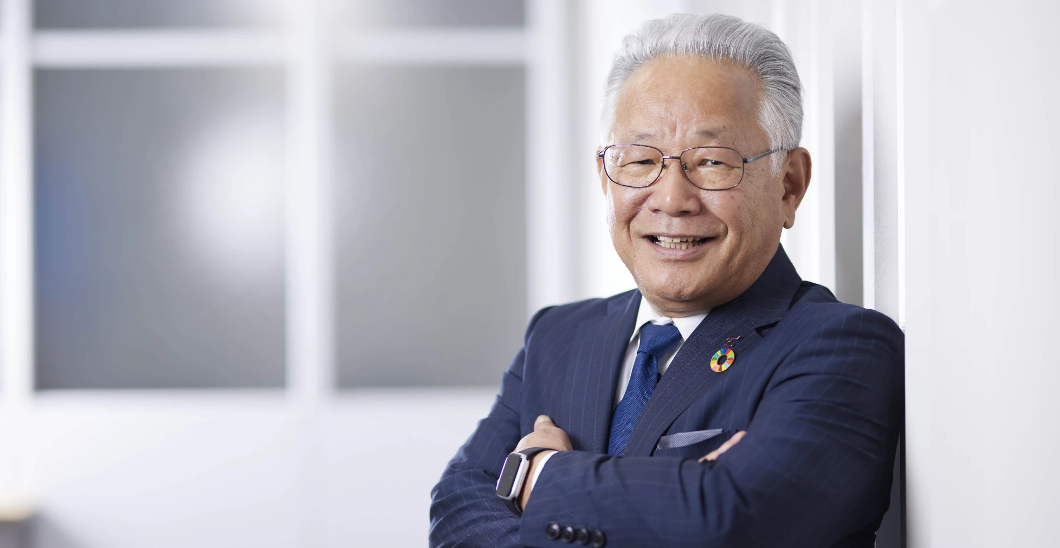 スーツ姿で腕を組み、笑顔を見せる代表取締役社長