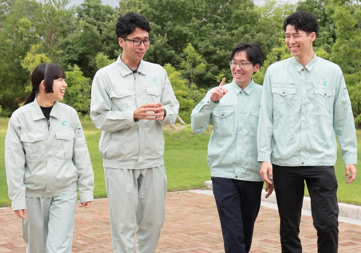 COSMOSの制服を着た4名の社員が屋外で談笑しながら歩いている様子