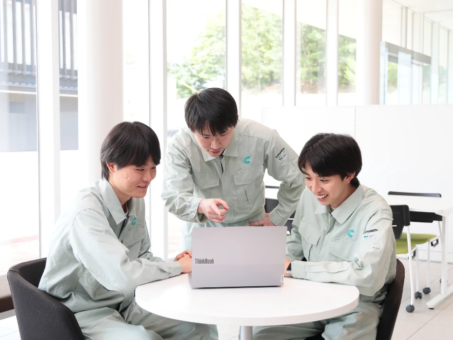 COSMOSの制服を着た男性社員3名がノートパソコンで作業している様子