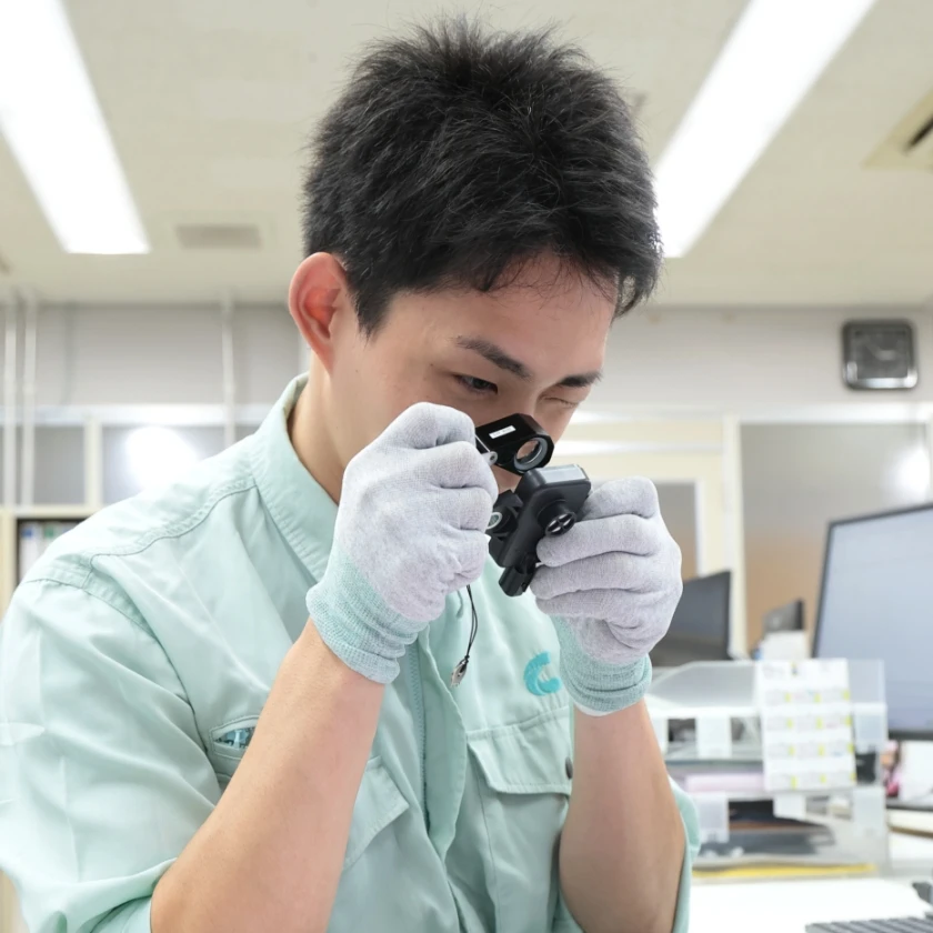 男性社員がルーペで製品を検査している様子
