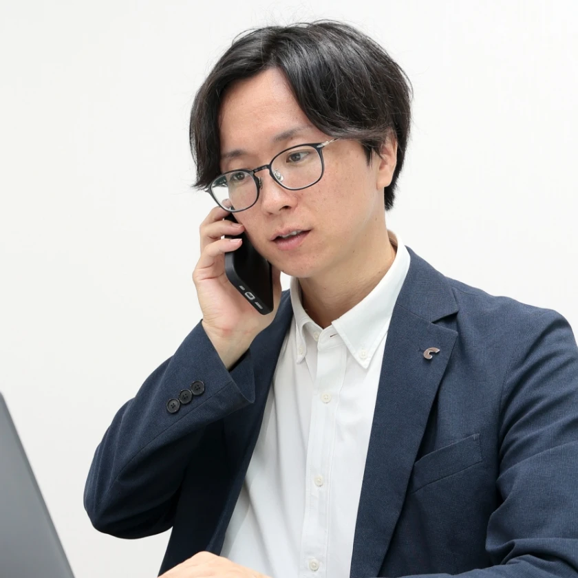 スーツ姿の男性社員が電話で対応している様子