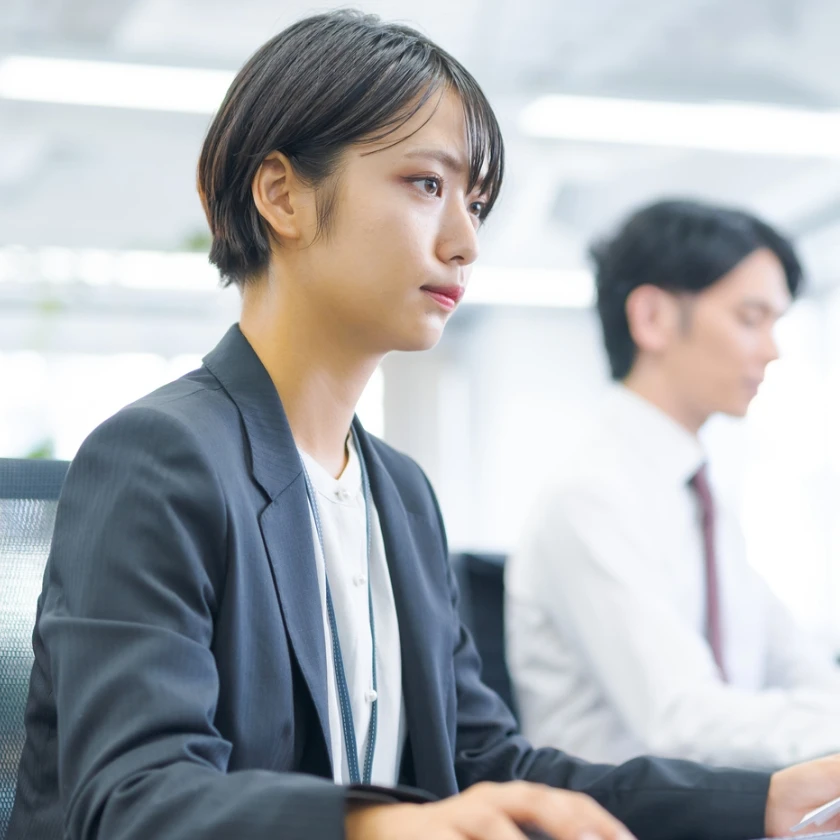 スーツ姿の女性社員が集中して業務に取り組んでいる様子
