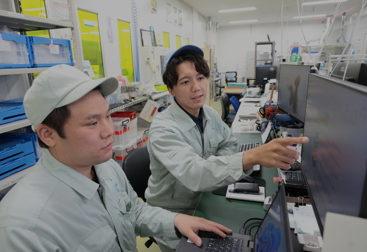 男性社員2名が協力してパソコンで作業している様子